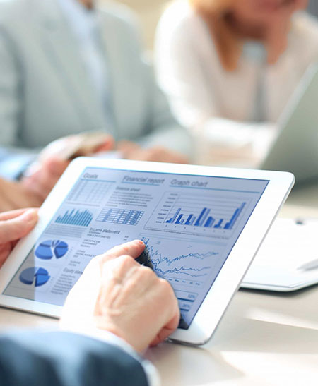 Pessoa analisando relatórios financeiros em um tablet, representando atuação tributária